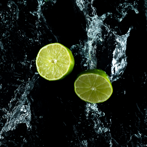 Two halves of a lime with water splashes on a black background