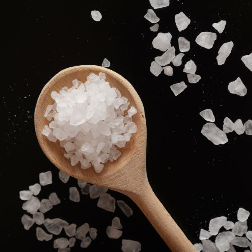 Wooden spoon filled with salt crystals on a black background